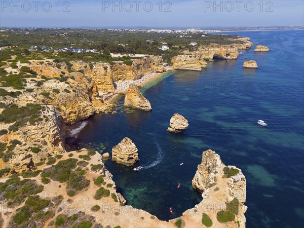 Aerial view of a rugged coastal landscape with rocky islands and boats in turquoise water, beach,