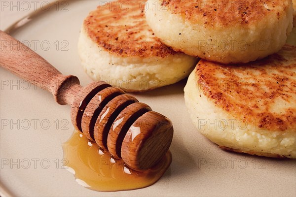 Cottage cheese pancakes, with honey, close-up, on a beige table, selective focus, no people