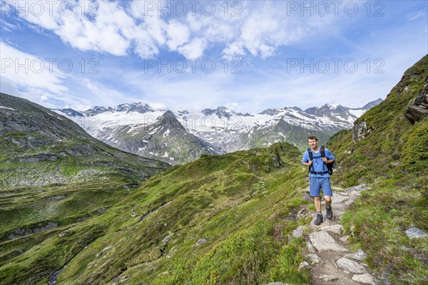 Mountaineer on hiking trail in picturesque mountain landscape, mountain peak with snow and glacier