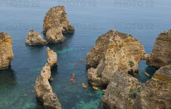 Kayakers explore the steep cliffs and coastline on the clear blue sea, Ponta da Piedade, point of
