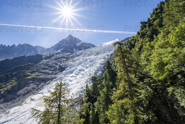 View of glacier Glacier des Bossons with sun star, behind summit of Aiguille du Midi, Chamonix,