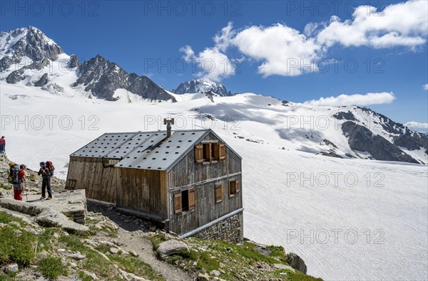 Mountaineer next to a mountain hut in front of a mountain landscape, Former hut of the mountain hut