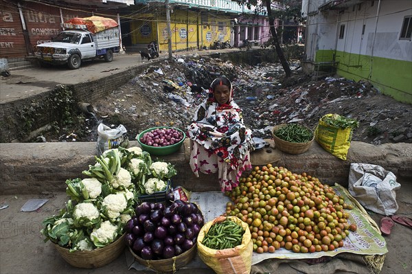 Vegetable seller in a street at Bodhgaya, India. Sewer is visible behind the woman