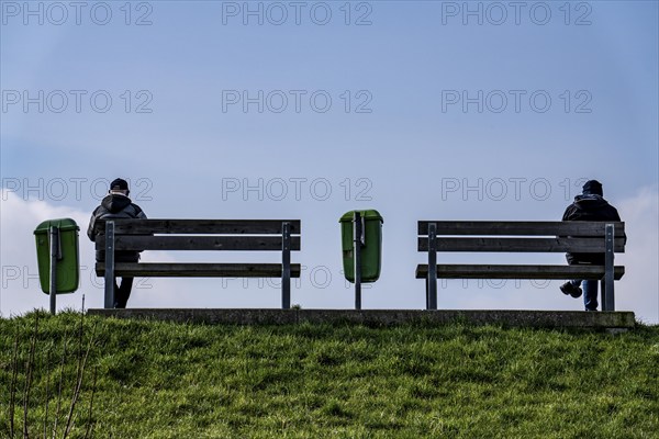 Benches on a dyke on the Weser in Bremerhaven, two people sitting symmetrically away from each
