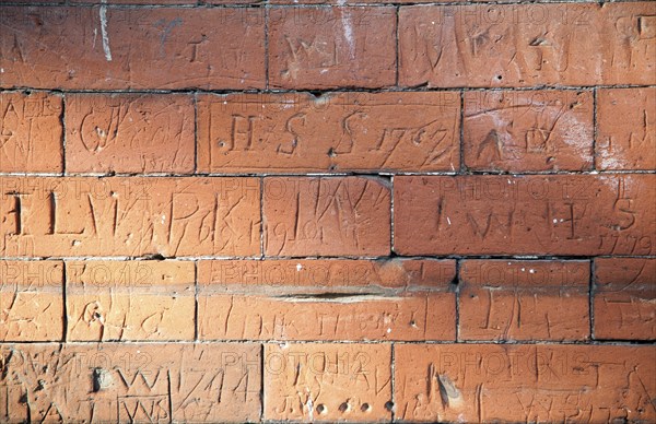 Eighteenth century children's graffiti scratched into red brick of former school building, Dedham,