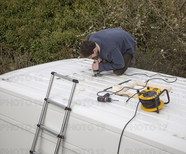 Cutting through roof of white metal camper van conversion to install ventilation window, UK