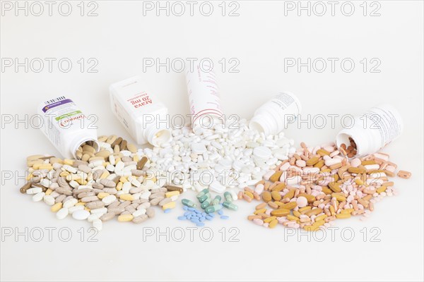 Various pills and tablets distributed around open medicine bottles