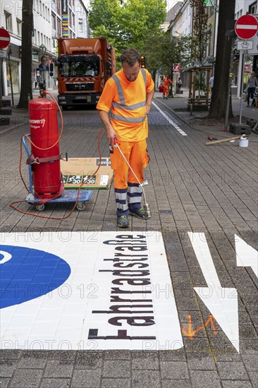Application of road markings for a cycle lane, Rüttenscheider Straße in Essen, in the shopping and