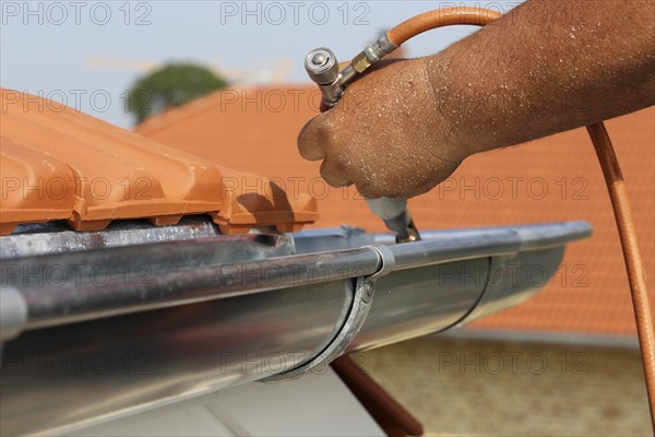 Roofer doing tinsmith work on a gutter