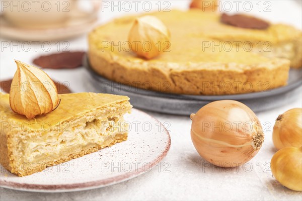 Autumn onion pie decorated with leaves and cup of coffee on gray concrete background. Side view,
