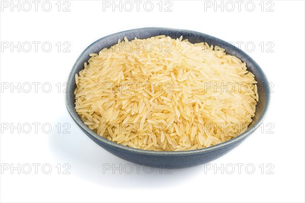 Blue ceramic bowl with raw golden rice isolated on white background. Side view, close up