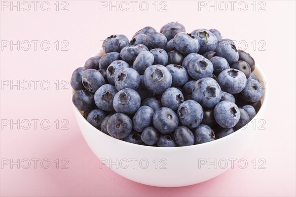 Fresh blueberry in white bowl on pink background. side view, close up