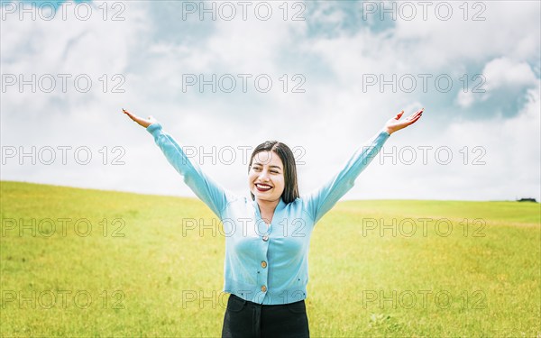 Portrait of beautiful girl spreading arms enjoying the countryside. Happy young woman spreading