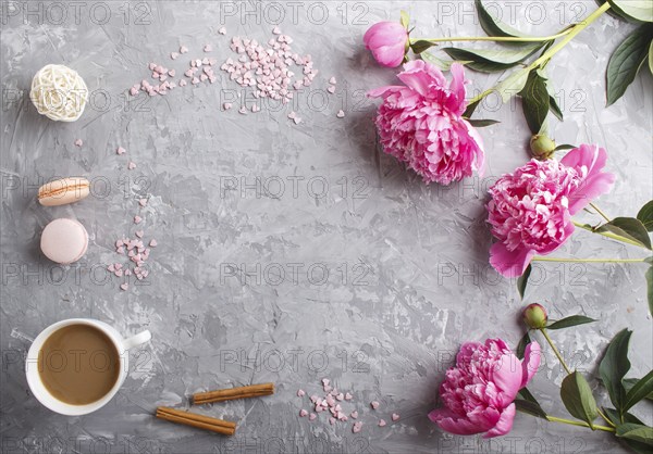 Pink peony flowers and a cup of coffee on a gray concrete background. Morninig, spring, fashion