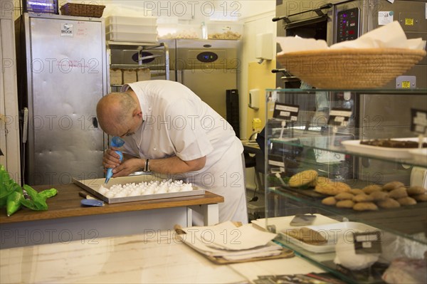 Expert baker craftsman making meringues inside the Little Bakehouse bakery shop, Devizes,