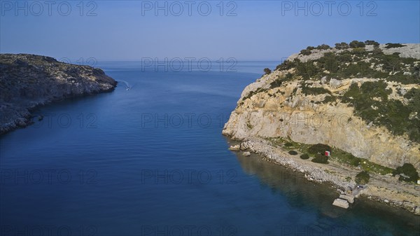 Drone shot, Rocky coast with a calm bay and blue water surrounded by natural beauty and sky,