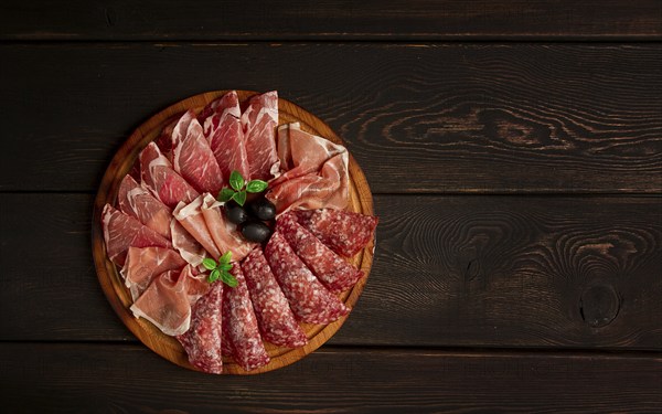 Assortment, sliced meat appetizer, prosciutto, salami and ham, with olives, breakfast, top view,