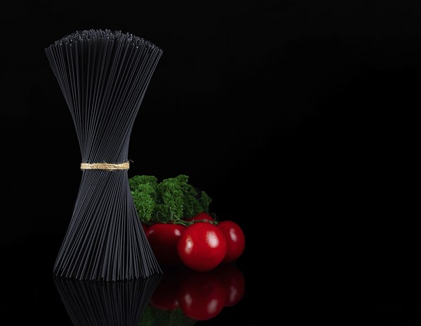 Bouquet, black spaghetti Nori, with ingredients, tomatoes and basil, on a black background,