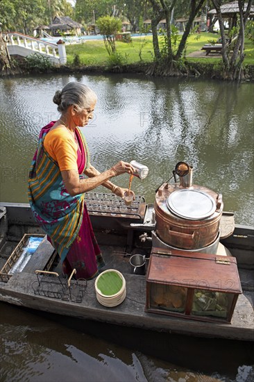 Tealady, 83 years old, making Indian tea on her boat, Backwaters, Kumarakom, Kerala, India, Asia