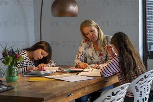 Homeschooling, during the lockdown in January 2021, mother helps her two daughters, at home,