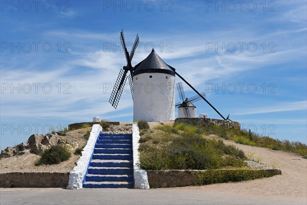 White windmill on a hill with blue steps and a clear blue sky in the background, Consuegra, Toledo,