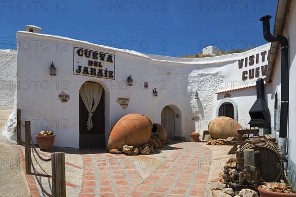 Rustic cave house with white walls and traditional decorations under a sunny sky, Cueva del Jaraiz,