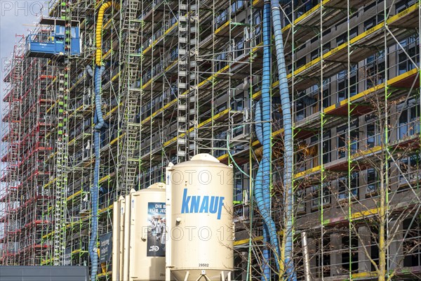 Large construction site, scaffolded shell of an office building complex, air hoses for construction