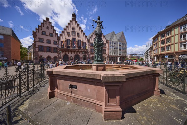 Fountain of Justice and Römer Town Hall on the Römerberg under a blue sky with cumulus clouds in