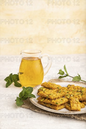 Traditional iranian dessert sohan with glass of green tea on a gray concrete background and linen