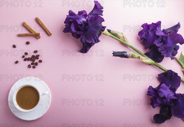 Purple iris flowers and a cup of coffee on pastel pink background. Morninig, spring, fashion
