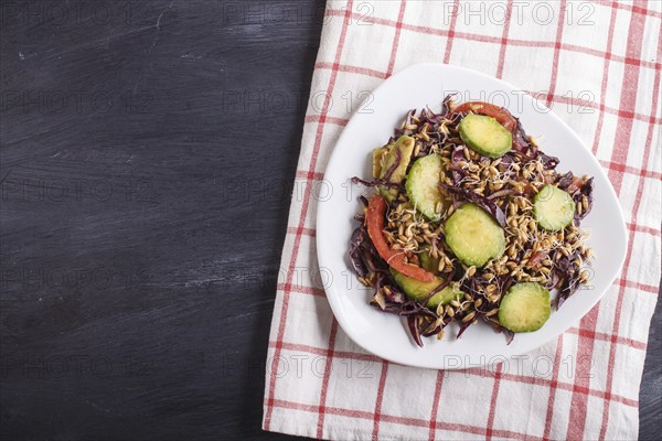 Vegetarian salad of purple cabbage, germinated wheat, tomatoes and avocado on linen tablecloth,