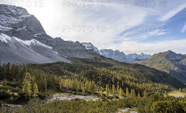Mountain panorama with steep rocky peaks, yellow-coloured larches in autumn, hike to the summit of
