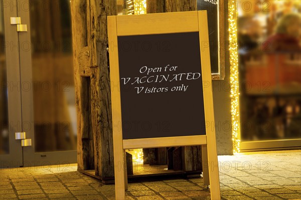 Street sign in front of a restaurant with the inscription Open for Vaccinated Visitors only
