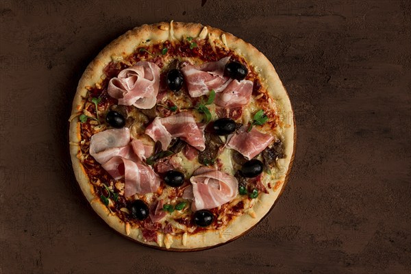 Pizza with prosciutto and mushrooms, bacon, olives, homemade, top view, no people