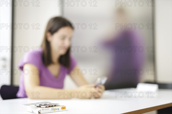 One hand holds a smartphone, in the foreground are painkillers. Berlin, 07.08.2024