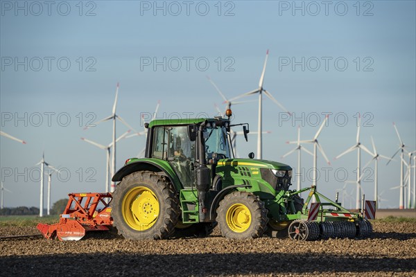 Farmer working in the fields, with a tractor, wind farm above the village of Lichtenau,