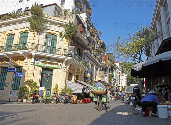 Vietnamese saleswoman with conical hat pushing her bicycle through the Old Quarter, Hanoi, Vietnam,