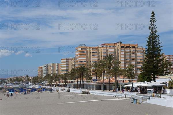 Beach promenade with high residential buildings and palm trees, summer sky, Torrox, Málaga