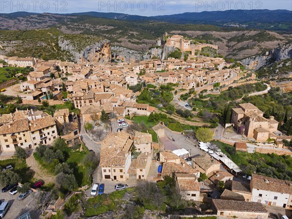 A charming village with historic tiled roofs and fortified buildings, nestled in the mountains,