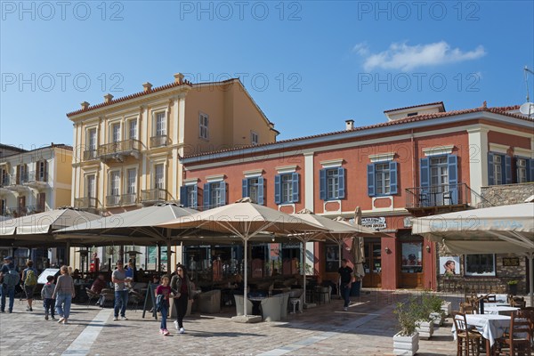 Historic city buildings with colourful facades and people strolling through a sunny city centre,
