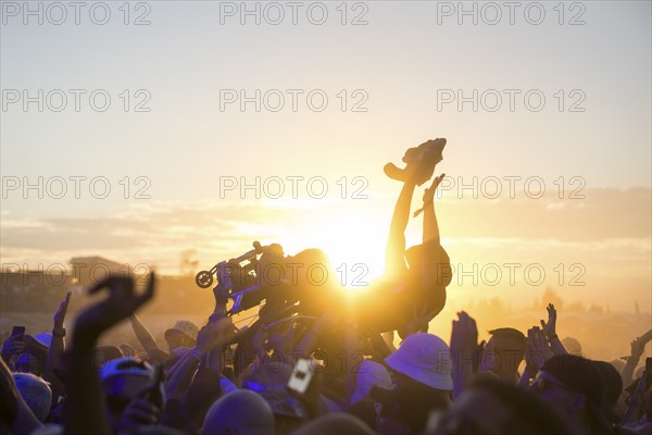 A wheelchair user crowdsurfing in front of sunset at the Highfield Festival on Friday, Störmthaler