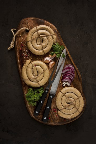 Raw spiral sausages, on a wooden board, top view, with spices, no people