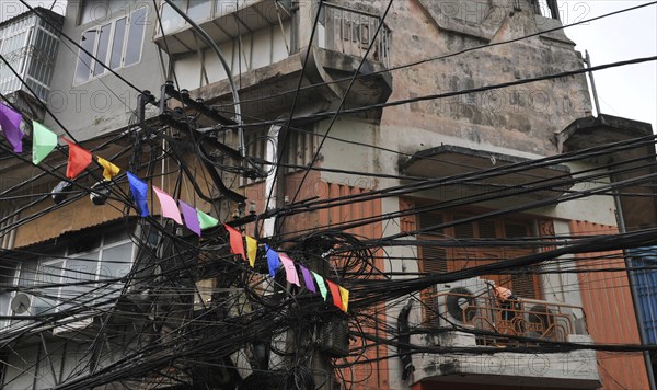 Messy entangled electricity, telecommunication wires, cables on poles in Hanoi, Vietnam, Asia