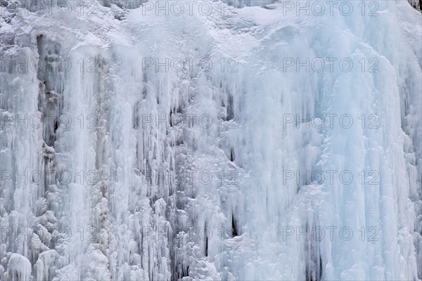 Texture of blue icicles on icy wall of rocks
