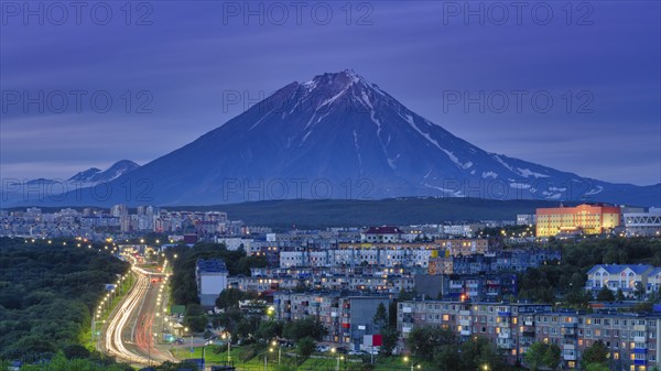 Panorama of night city of Petropavlovsk-Kamchatsky on background cone of volcano, urban development