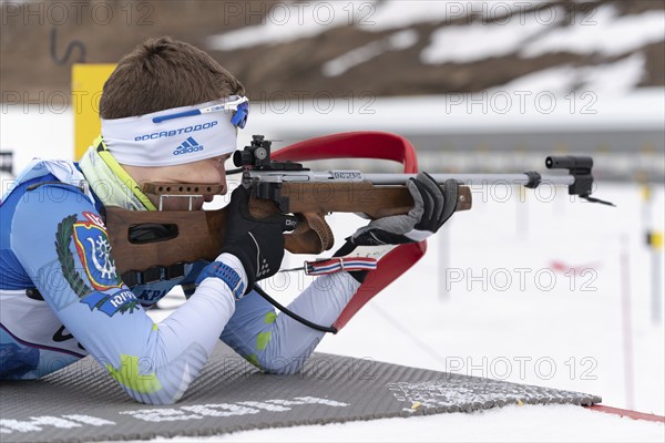 Sportsman biathlete Morilov Mikhail Khanty-Mansiysk aiming rifle shooting prone position. Biathlete