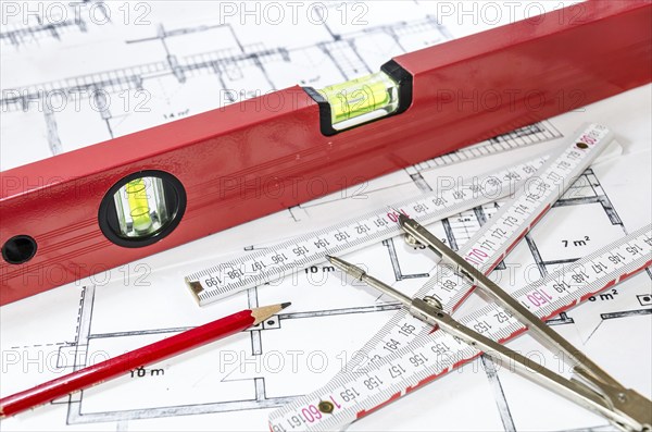 Spirit level, pencil, yardstick and compass calipers on a construction plan