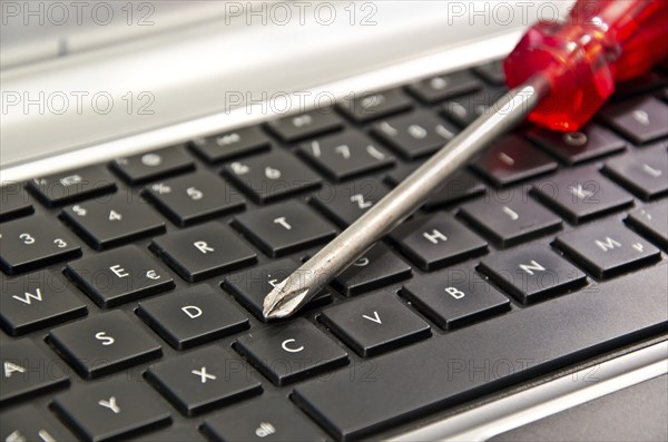 Screwdriver on computer keyboard symbolizing IT maintenance