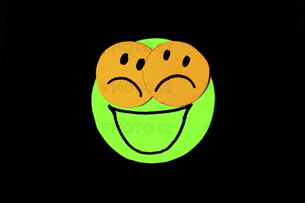 Paper cutouts of circles with faces drawn on black background. concept of pretending to be happy
