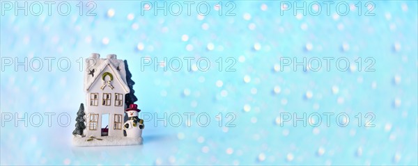 Christmas or New Year snow house decoration, snowman, blue bokeh background with lights banner